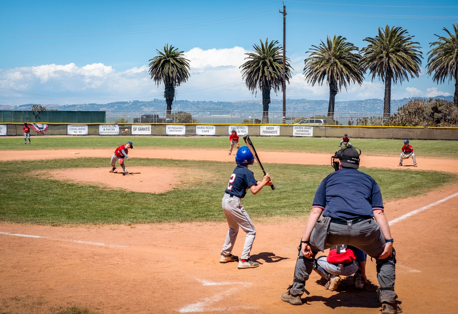 A young baseball batter awaits a pitch on a sunny field